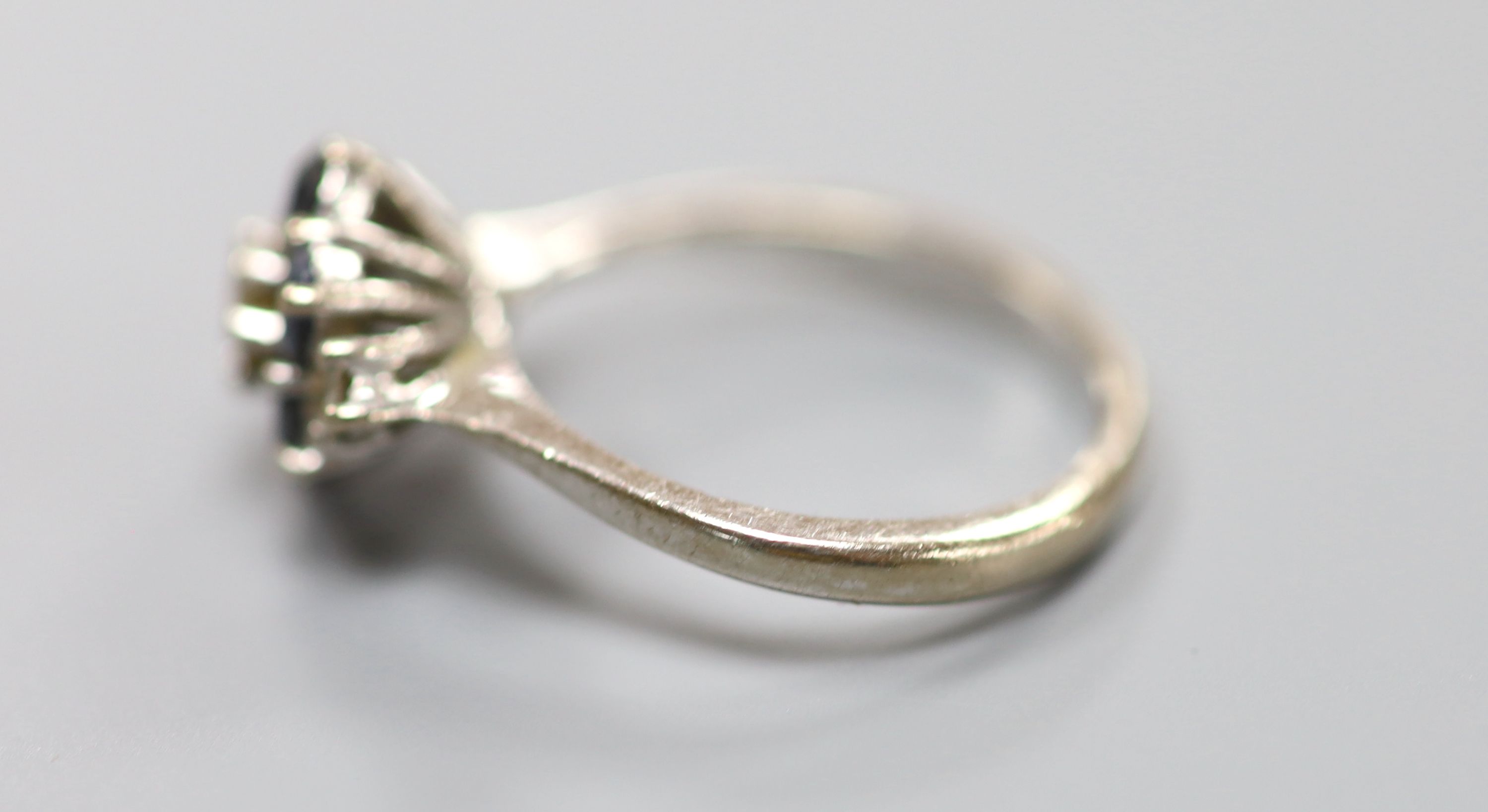 A white metal (stamped 18ct), sapphire and diamond cluster ring, size M, gross 4.2 grams.